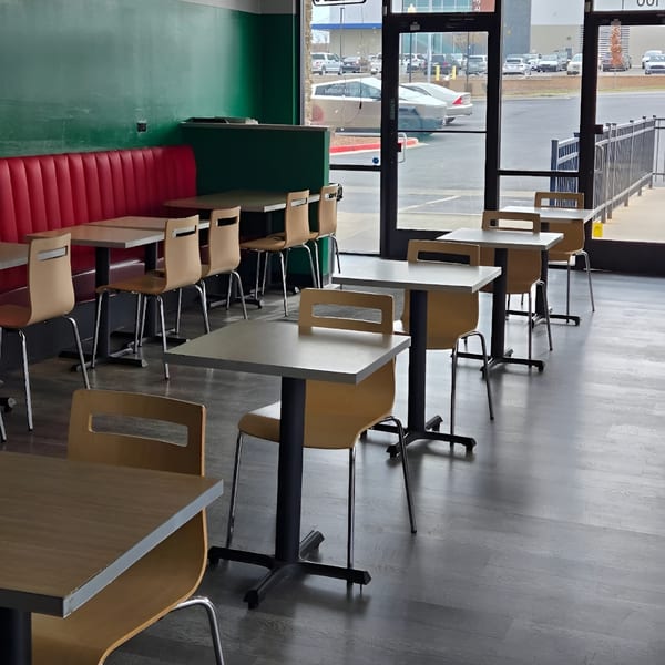 Empty dining area at Chili Shack with red booths, green walls, and light brown tables and chairs.
