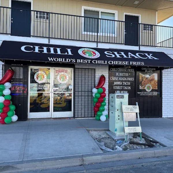 Exterior of Chili Shack restaurant with a black awning, menu boards, and red, green, and white balloons.