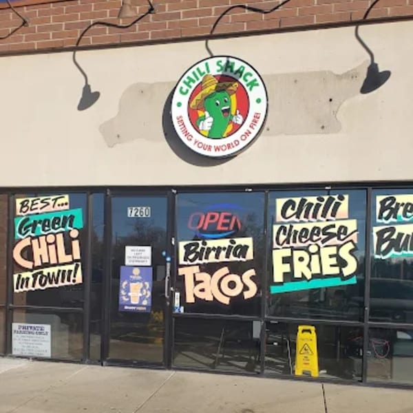 The Chili Shack storefront with a chili pepper logo and signs for green chili, birria tacos, and chili cheese fries.